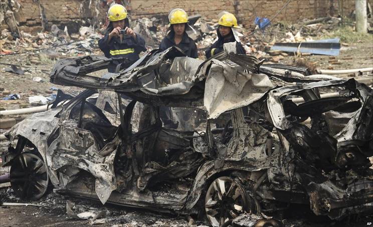 Firefighters by a burned car in Nanjing, China (28 July 2010)